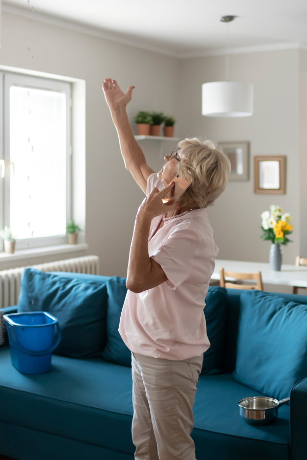 image of an elderly woman calling someone about water damage in their home