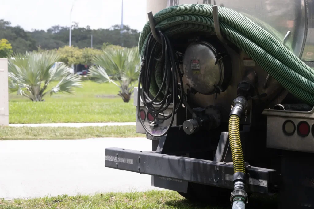 Rear view of a tanker truck with coiled green and yellow hoses attached.