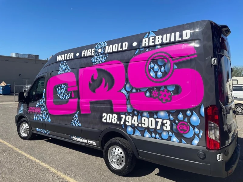 Black van with large pink "CRS" letters and blue water drop graphics advertising water, fire, mold restoration services. professional restoration company