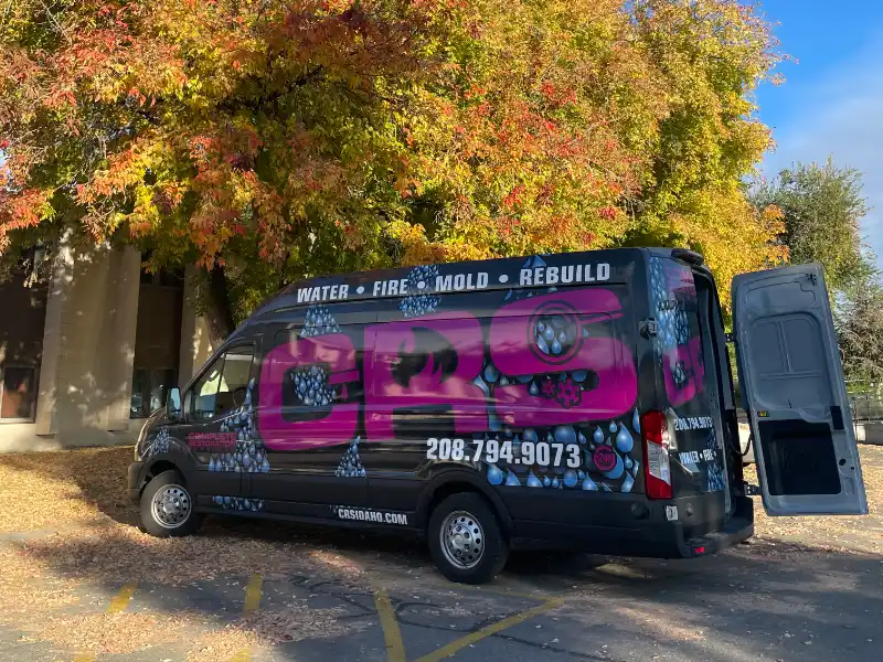A black van with CRS logo parked near trees with autumn leaves. damage restoration services