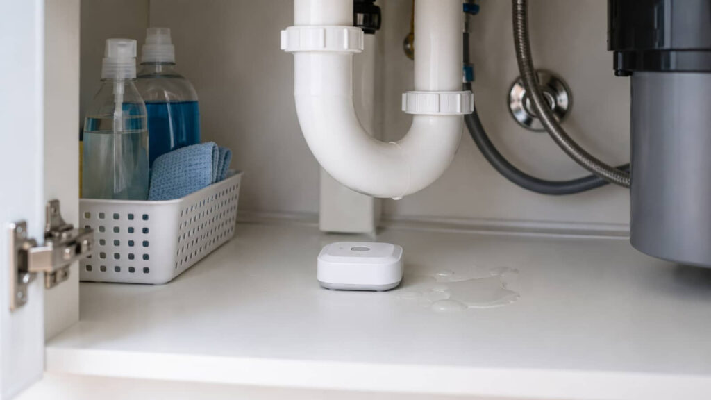 Leak sensor under a sink beside a small water spill.