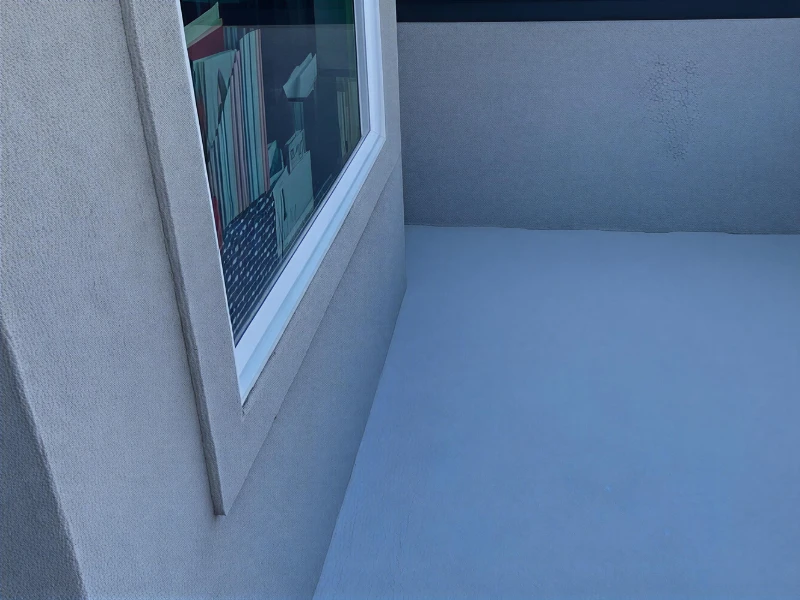 Empty outdoor balcony with textured gray walls and a window reflecting books inside. waterproof deck systems