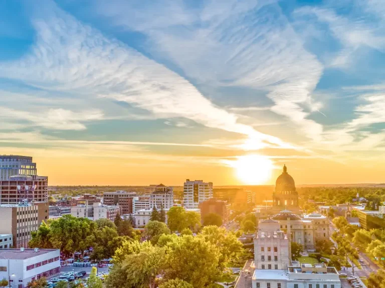 Sunset over a cityscape with a domed capitol building and scattered clouds in the sky. water damage restoration in Boise