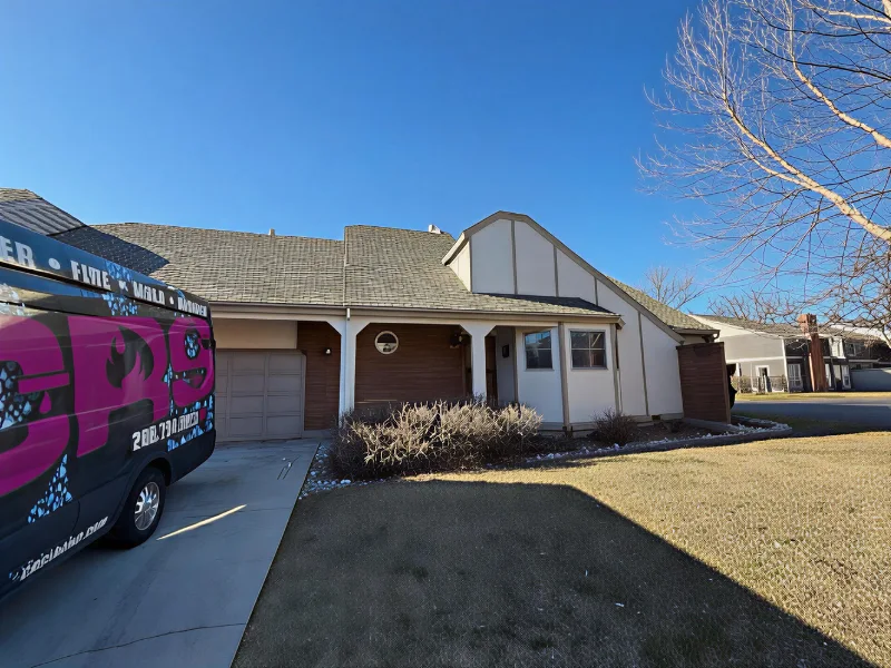 Suburban house with a garage and a van parked on the driveway under a clear blue sky. damage restoration services