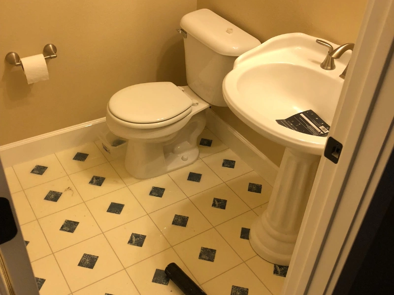Small bathroom with a white toilet and pedestal sink on a tiled floor with black diamond patterns. sewage cleanup