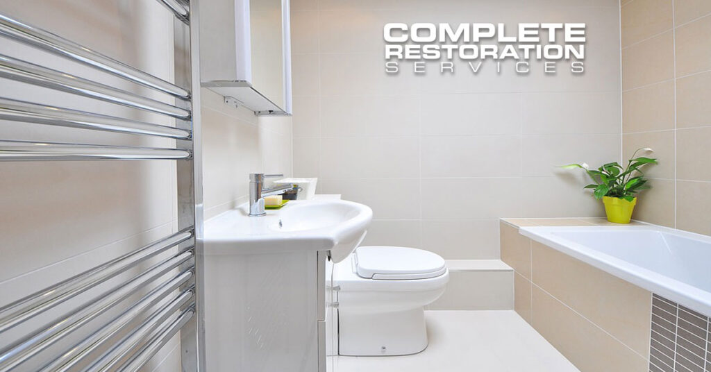 Modern clean bathroom with white fixtures and a small green plant on the bathtub edge.