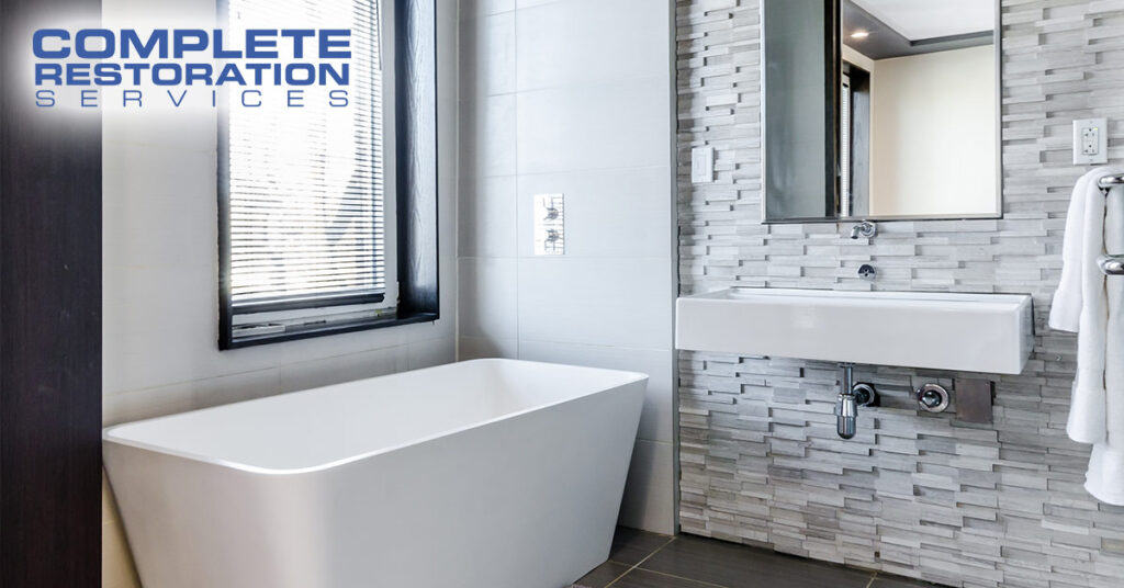 Modern bathroom with a freestanding bathtub, wall-mounted sink, and a large mirror above the sink.